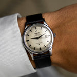 Reloj vintage Omega Constellation 168.001 de 1963 en la muñeca, esfera plateada y fecha a las 3