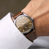 Montre vintage Omega Jumbo 2639-12 de 1952 au poignet, cadran chocolat patiné et bracelet cuir marron