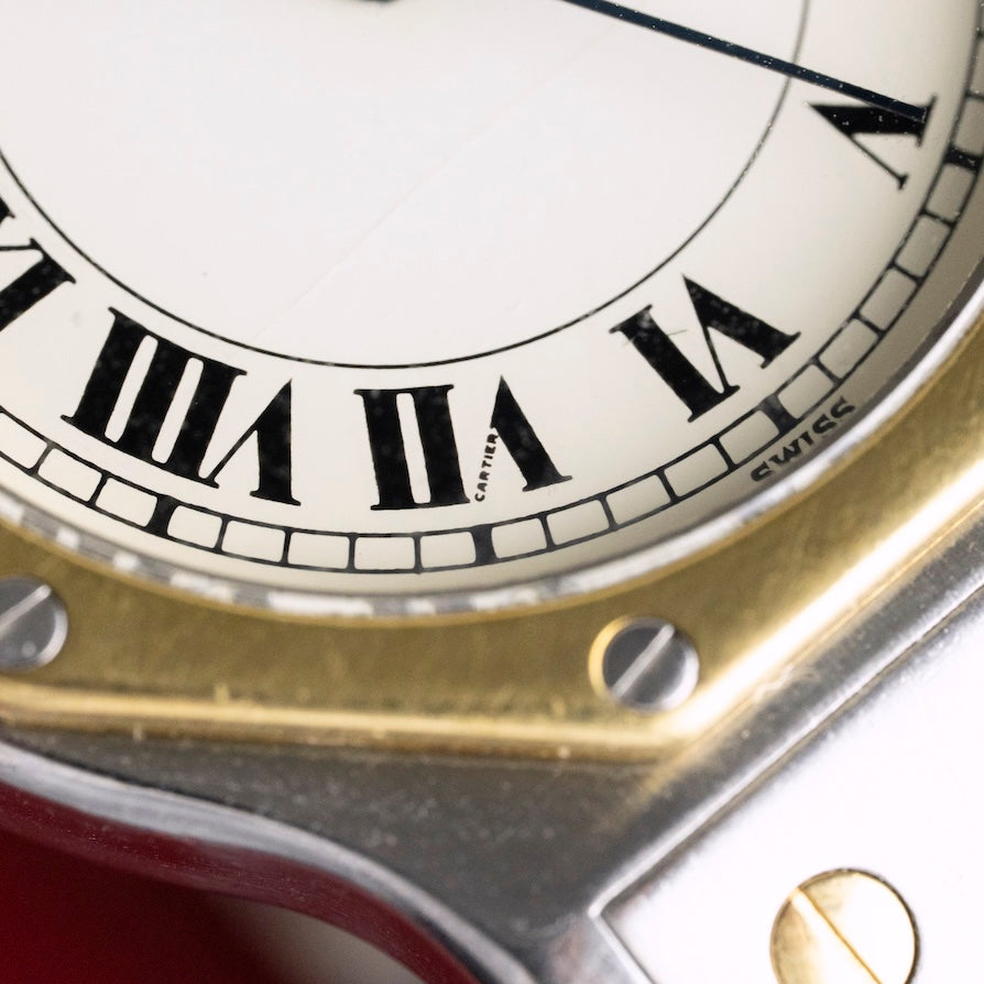 Gros plan sur la lunette octogonale en or jaune 18 carats de la Cartier Santos, montre vintage