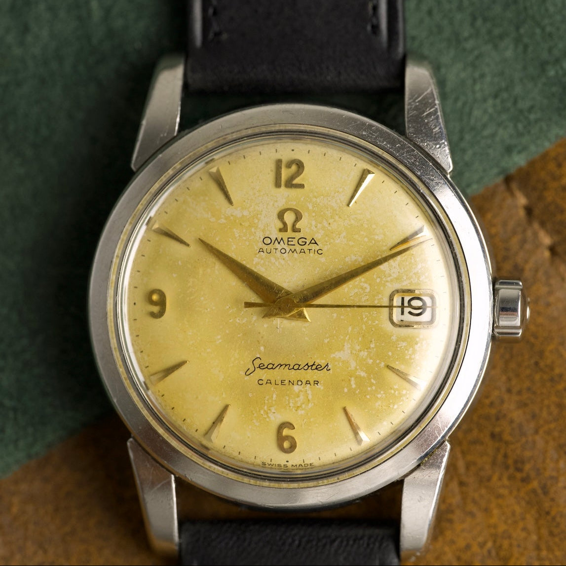 Esfera dorada con pátina del Omega Seamaster Calendar, números arábigos y ventanilla de fecha, reloj antiguo